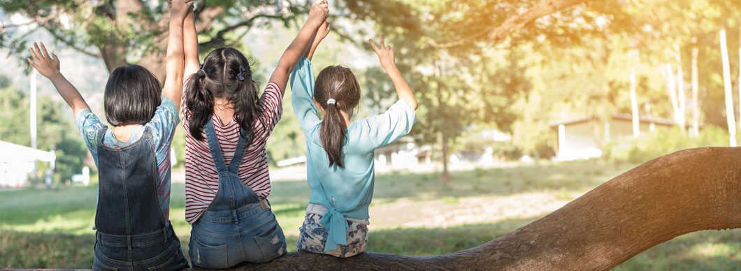 3 petites filles de dos sur une branche d'arbre 